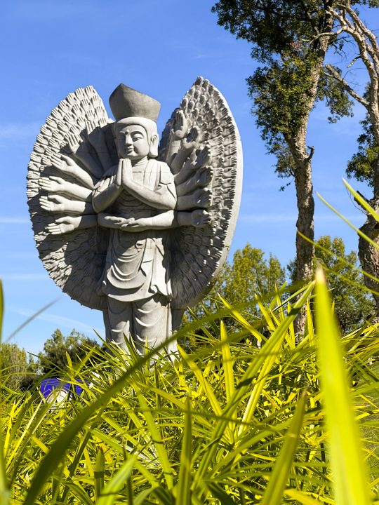 White Buddhist angel figure rising above tropical plants