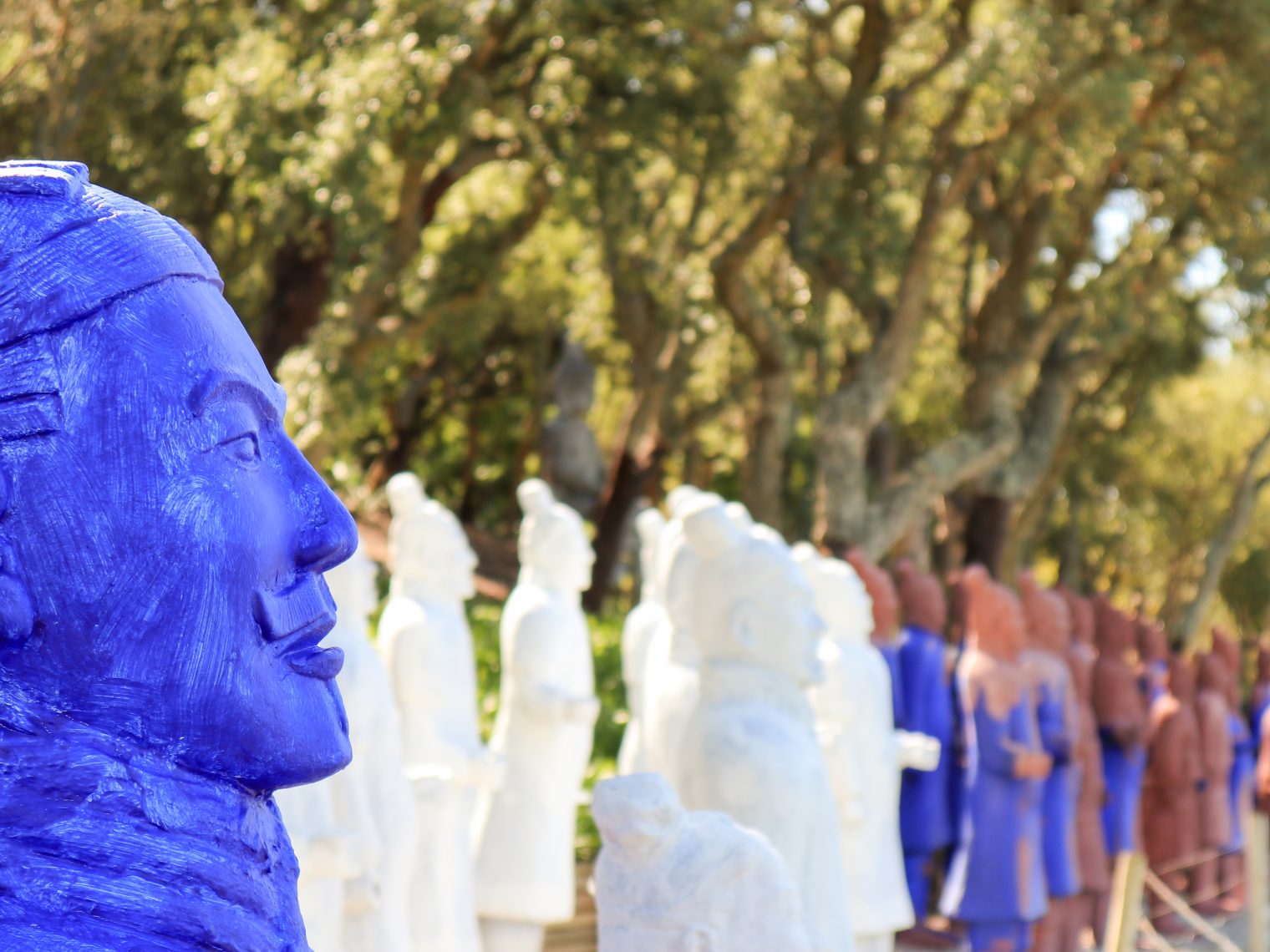 Row of colored statues among trees at Buddha Eden garden