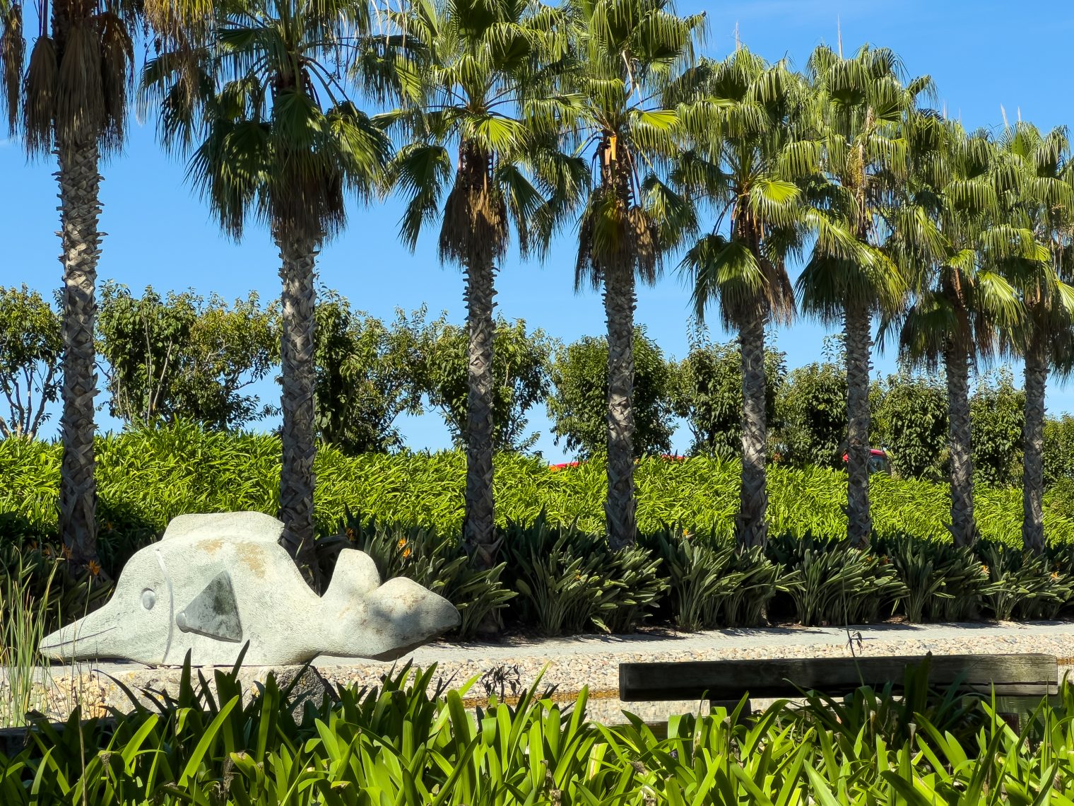 White fish sculpture among palm trees and tropical plants