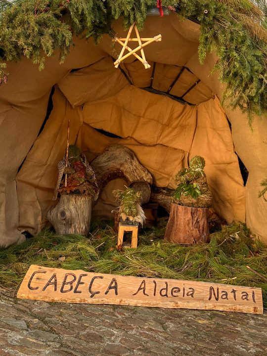 Nativity scene decorated with natural materials and wooden welcome sign in Portuguese